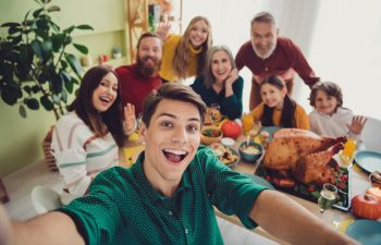Smiling three-generaion family at Thanksgiving dinner table taking a photo