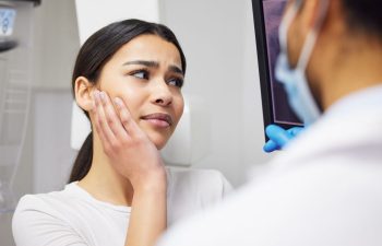 A woman with toothache and a dentist revising dental X-ray